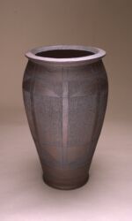 Tall urn with finely scored arrowhead design. Bronze/black. Height 75cm/30”.
